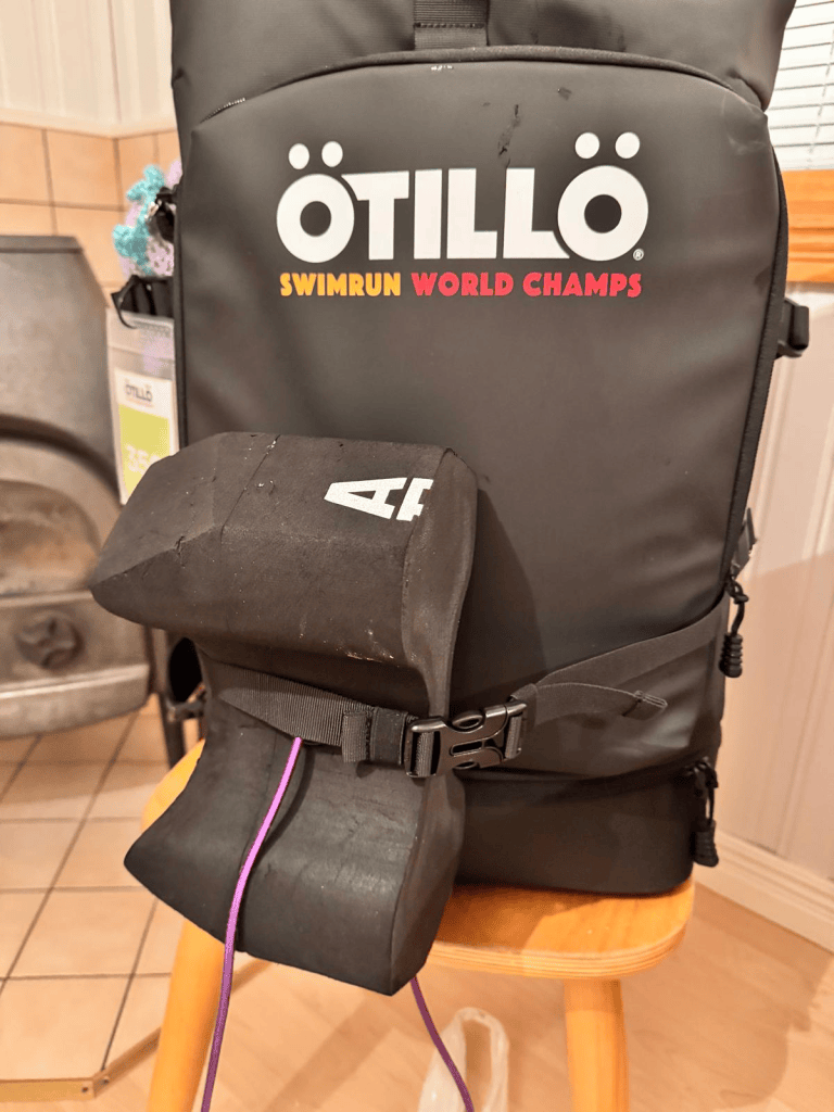 Close-up of an ÖTILLÖ Swimrun World Championships backpack with a neoprene swim buoy attached to its side.
